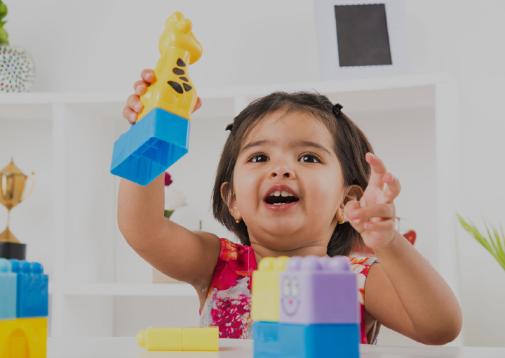 A joyful child playing with colorful building blocks at Krityam Montessori School in Manyata Tech Park, Bengaluru."